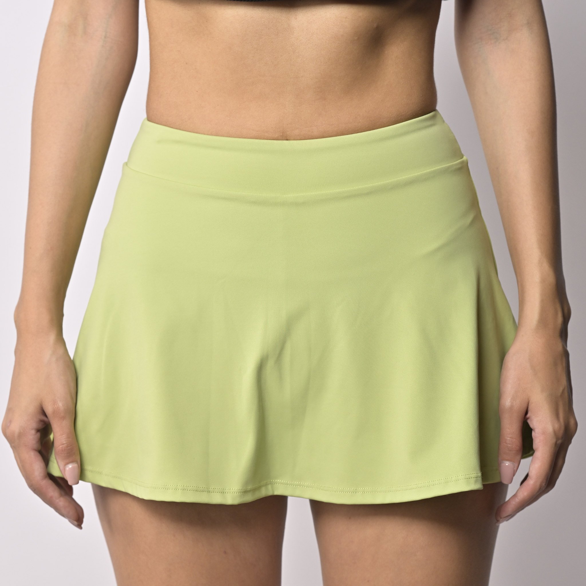 Light green sports skort worn by a woman on a plain background