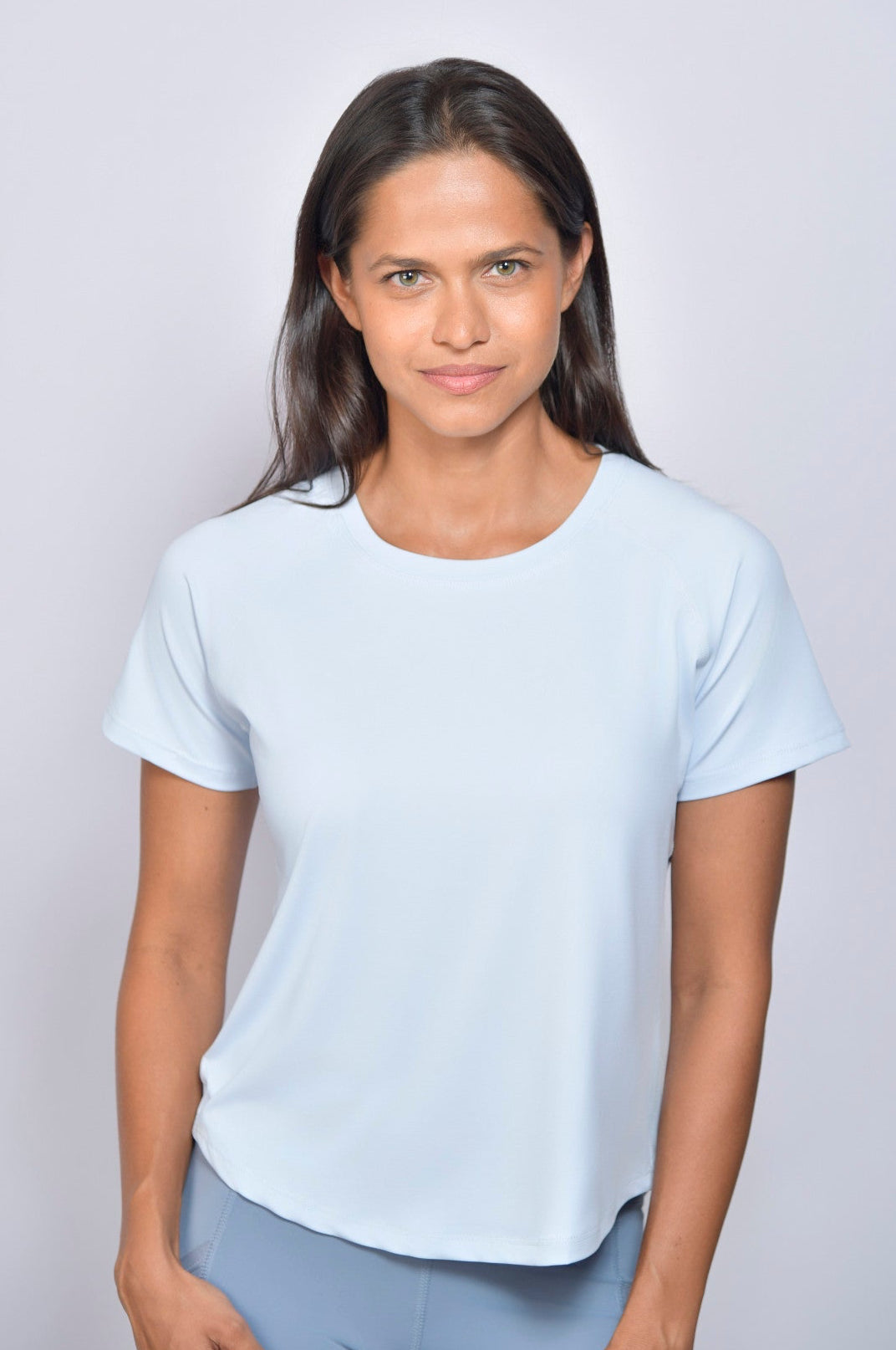 Woman wearing a light blue t-shirt and gray leggings against a white background