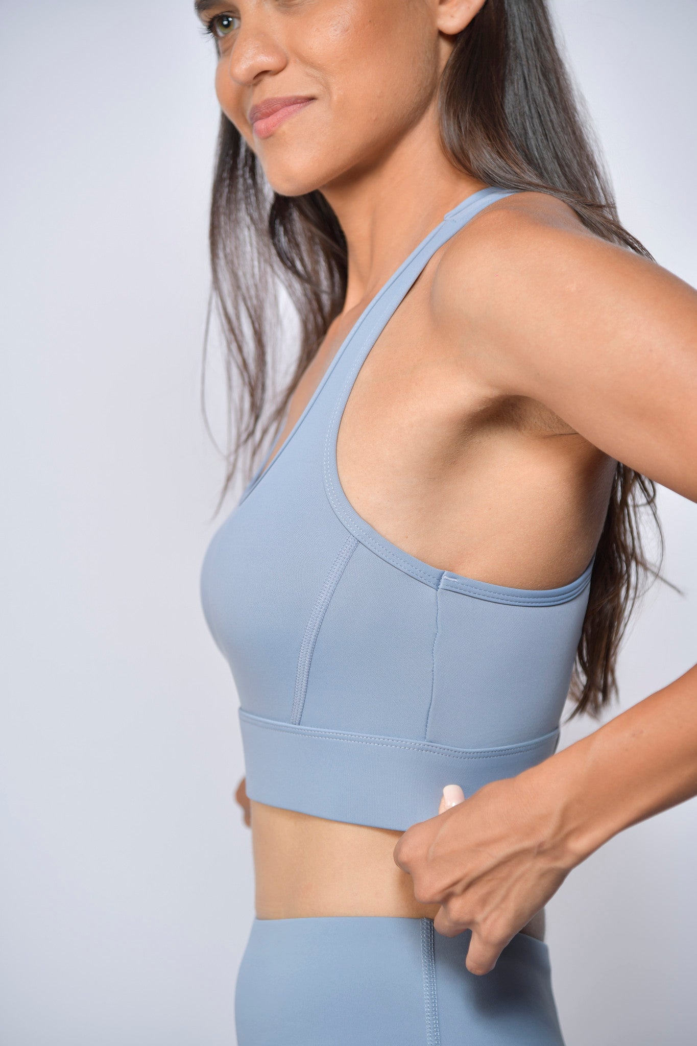 Woman wearing a light blue sports bra and leggings against a plain background