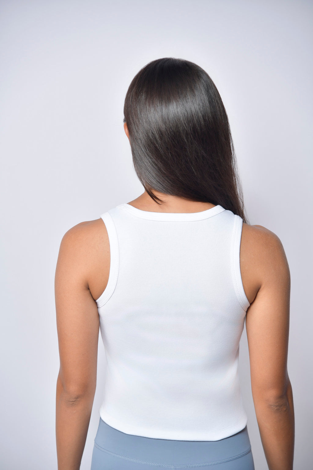 Back image of woman wearing a white tank top