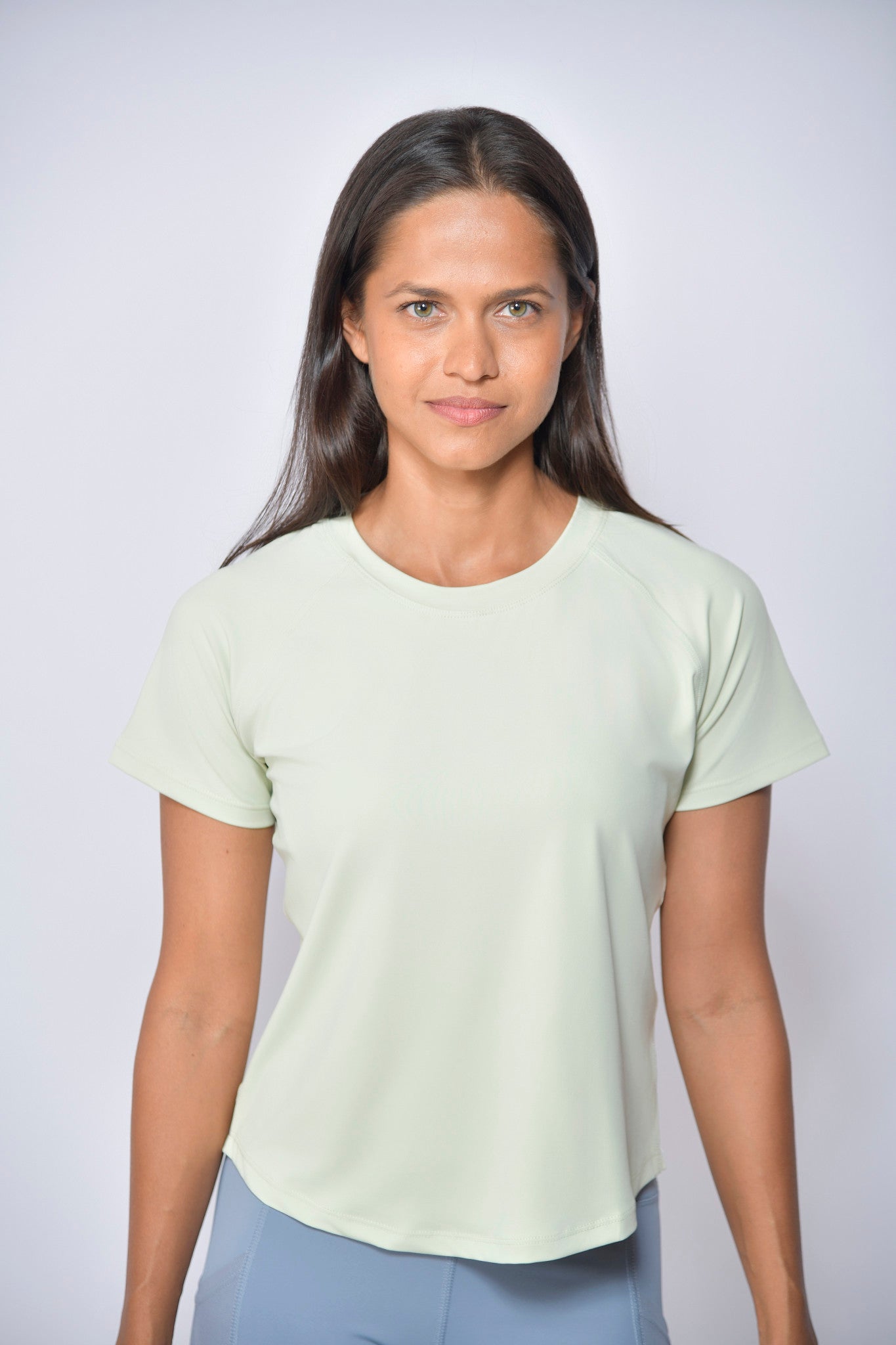 Woman wearing a light green sports t-shirt against a white background