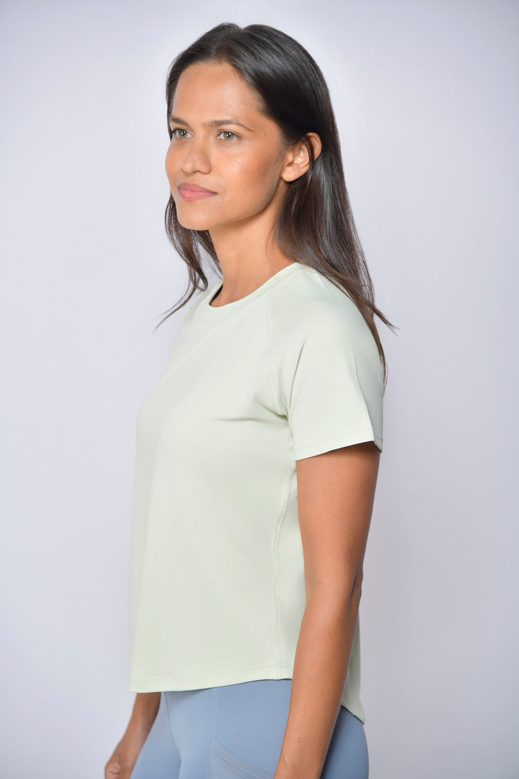 Woman wearing a light green sports t-shirt against a white background