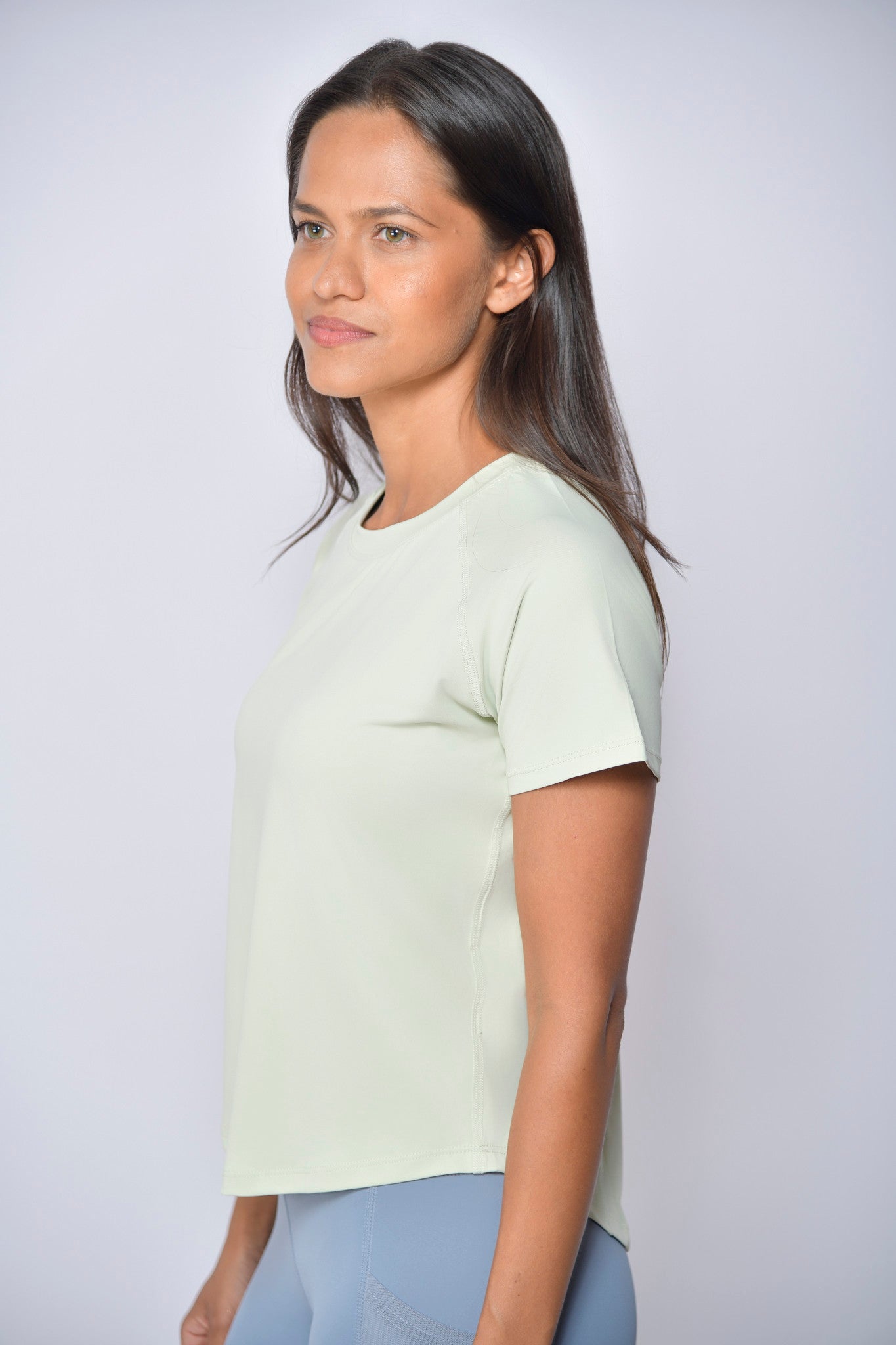 Woman wearing a light green sports t-shirt against a white background