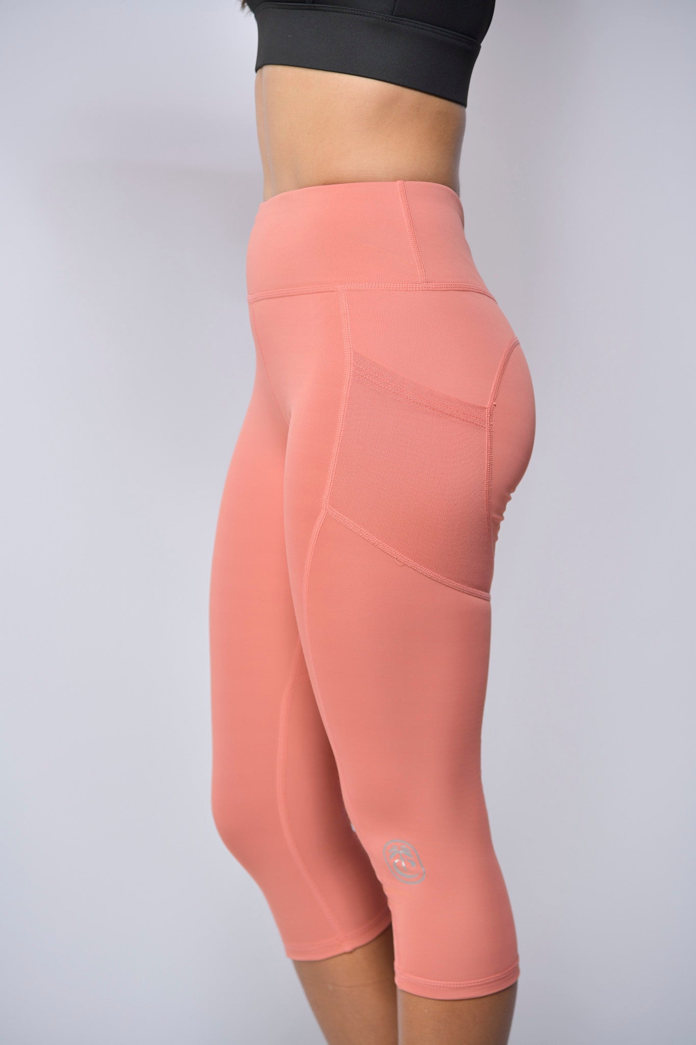 Peach athletic leggings worn by a woman on a light gray background